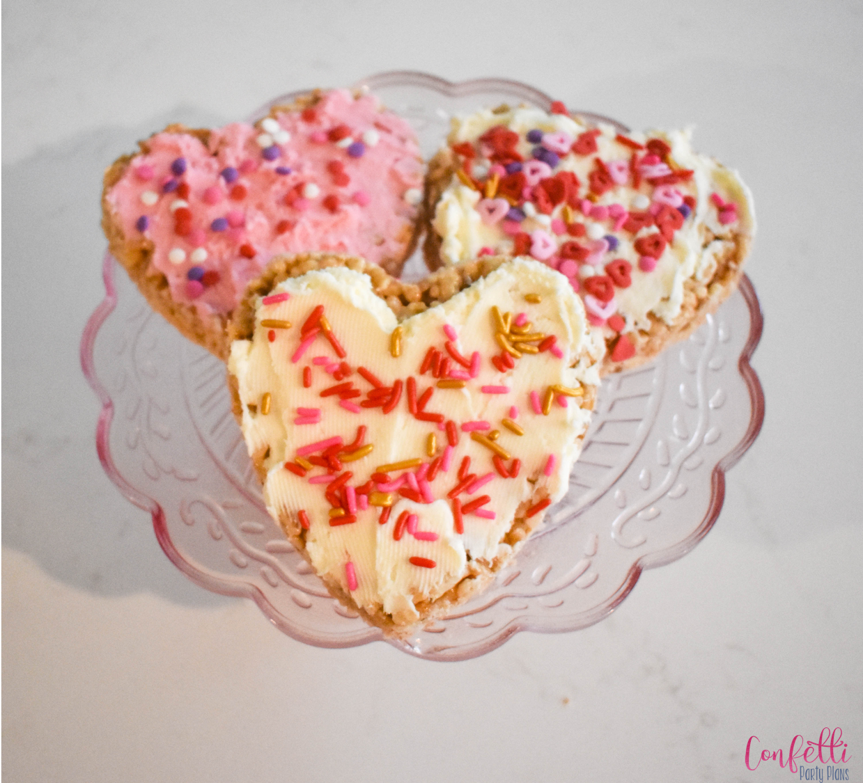 heart shaped rice crispy treats decorated for Valentines day with pink and red sprinkles