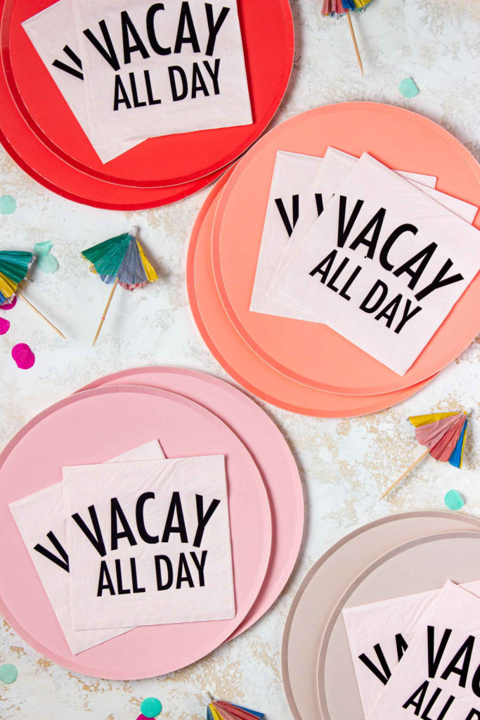 dark pink, coral, pink, and light pink ombre paper plates, light pink Vacay All Day paper napkins, and rainbow paper drink umbrellas included in the Summer Memories in Moments Unwrapped craft and activity subscription box for kids