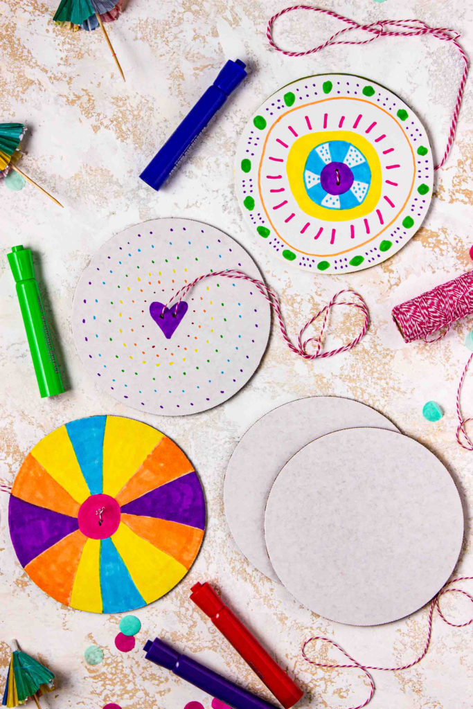white and rainbow cardboard summer spinners as a kids fidget activity included in a Memories in Moments Unwrapped box filled with summer themed crafts and activities for kids and busy moms to survive summer break at home