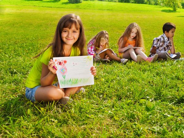 kids coloring and drawings in a grassy field happily playing outside for an entertaining kids activity