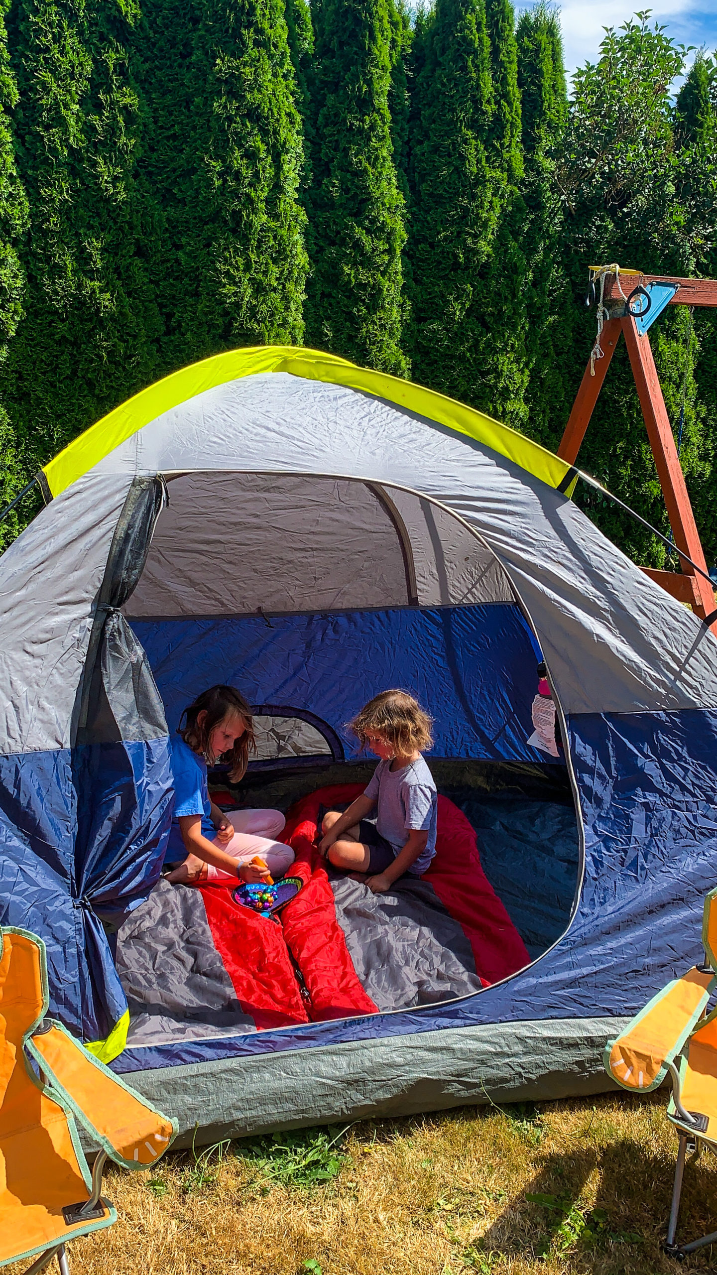 kids playing games in a backyard tent- Travel blogger Nikki Harrington shares seven ideas that will turn your backyard into the ultimate (easy) family camping adventure!